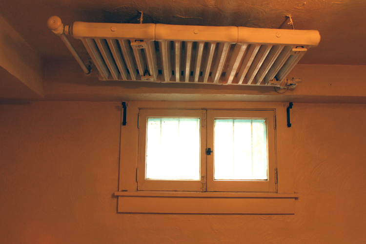 Steam radiator mounted over basement window